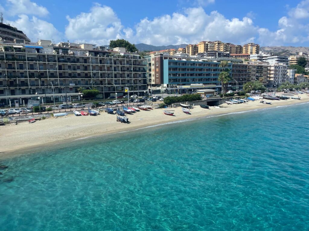 Foto della spiaggia di Messina vista dal traghetto che attraversa lo Stretto.