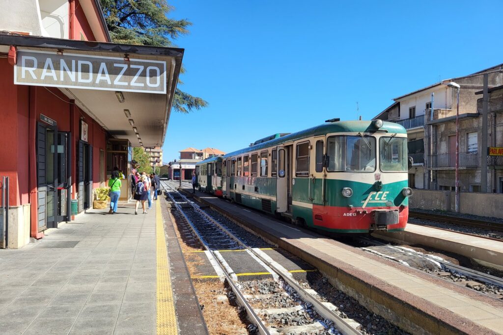 Strada del Vino dell'Etna 2026: treno, cantine e degustazioni in autunno 1 Automotrice verde e rossa della Ferrovia Circumetnea ferma al binario della stazione di Randazzo, sotto il sole